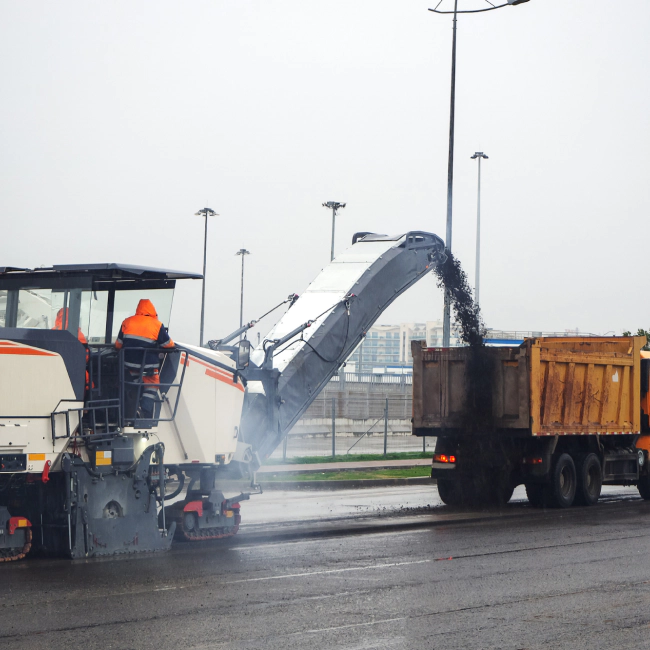 worker with an asphalt crusher machine pouring it into the street